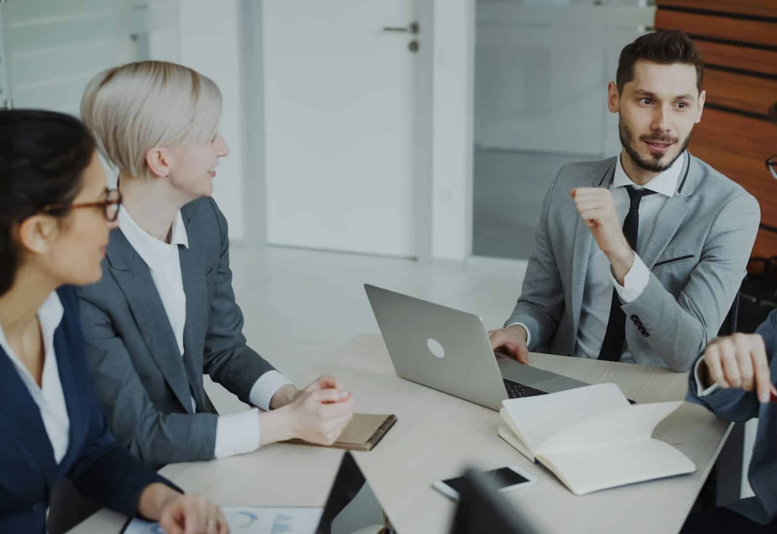 Salesforce Account Engagement mit Beyond Digital: Vier Fachleute besprechen sich an einem Tisch mit Laptop und Notizbuch
