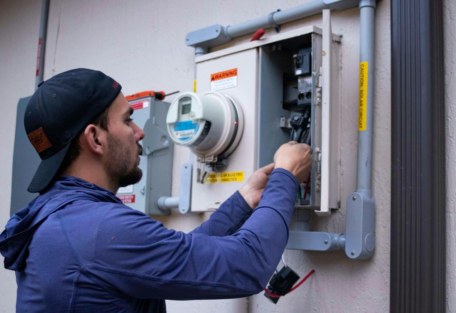 Salesforce Field Service mit Beyond Digital: Servicetechniker arbeitet an einem Stromzähler an einer Hauswand