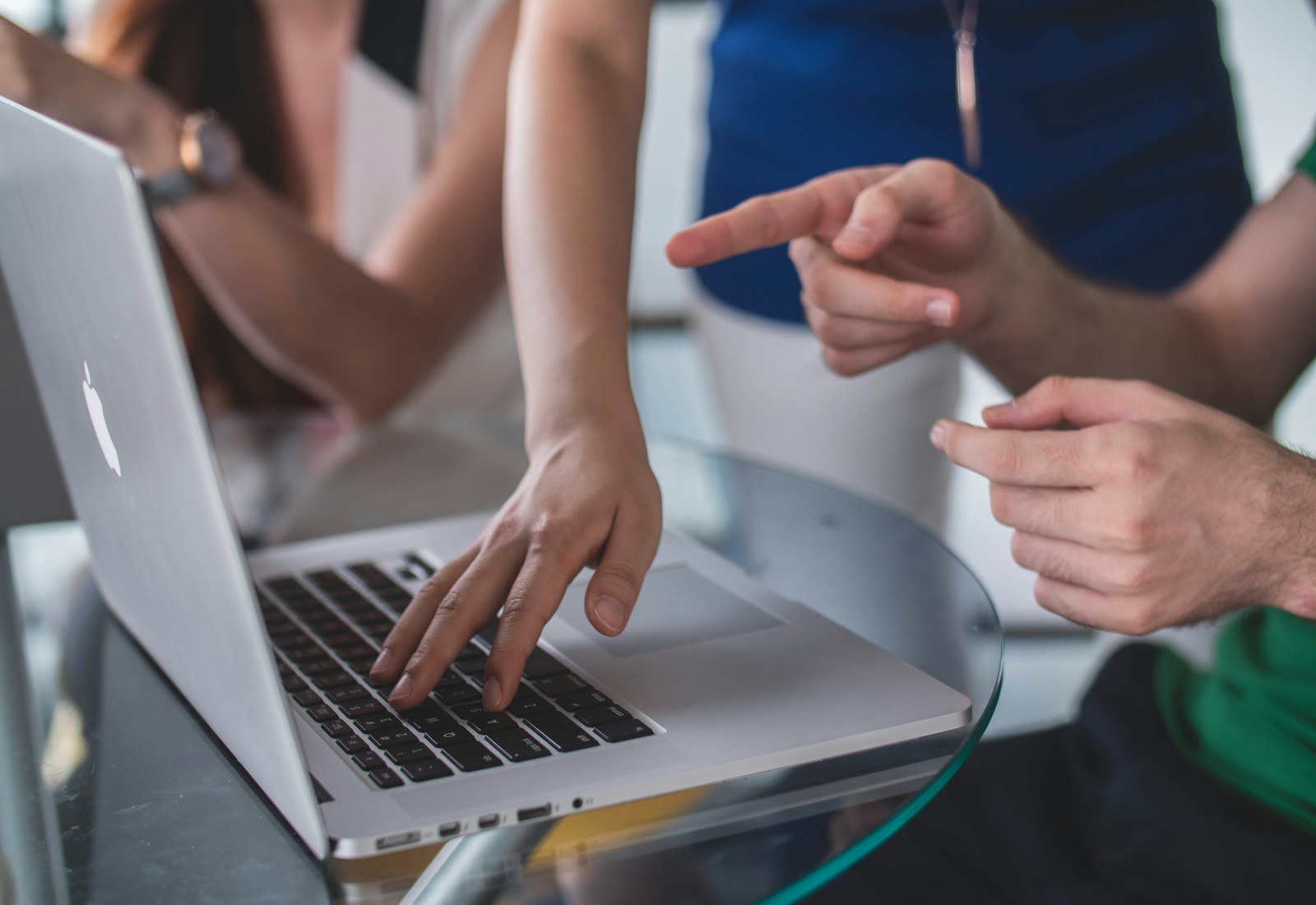 MuleSoft Beratung von Beyond Digital: Mehrere Hände zeigen im Gespräch auf einen aufgeklappten Laptop