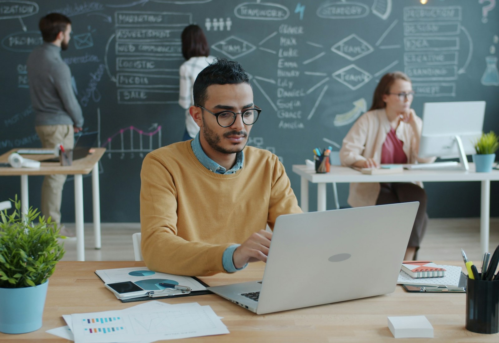 MuleSoft Einführung mit Beyond Digital: Mann arbeitet am Laptop vor einer Tafel mit skizzierter Mindmap in einem modernen Büro