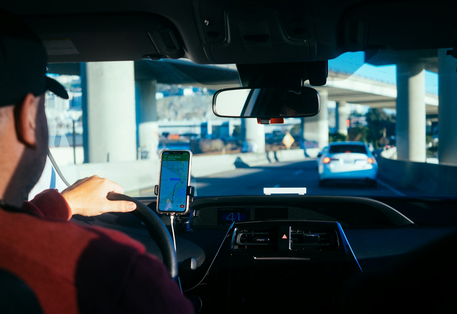Salesforce Automotive Cloud Beratung von Beyond Digital: Fahrer am Steuer, am Armaturenbrett ist ein Smartphone mit Navigations-App befestigt
