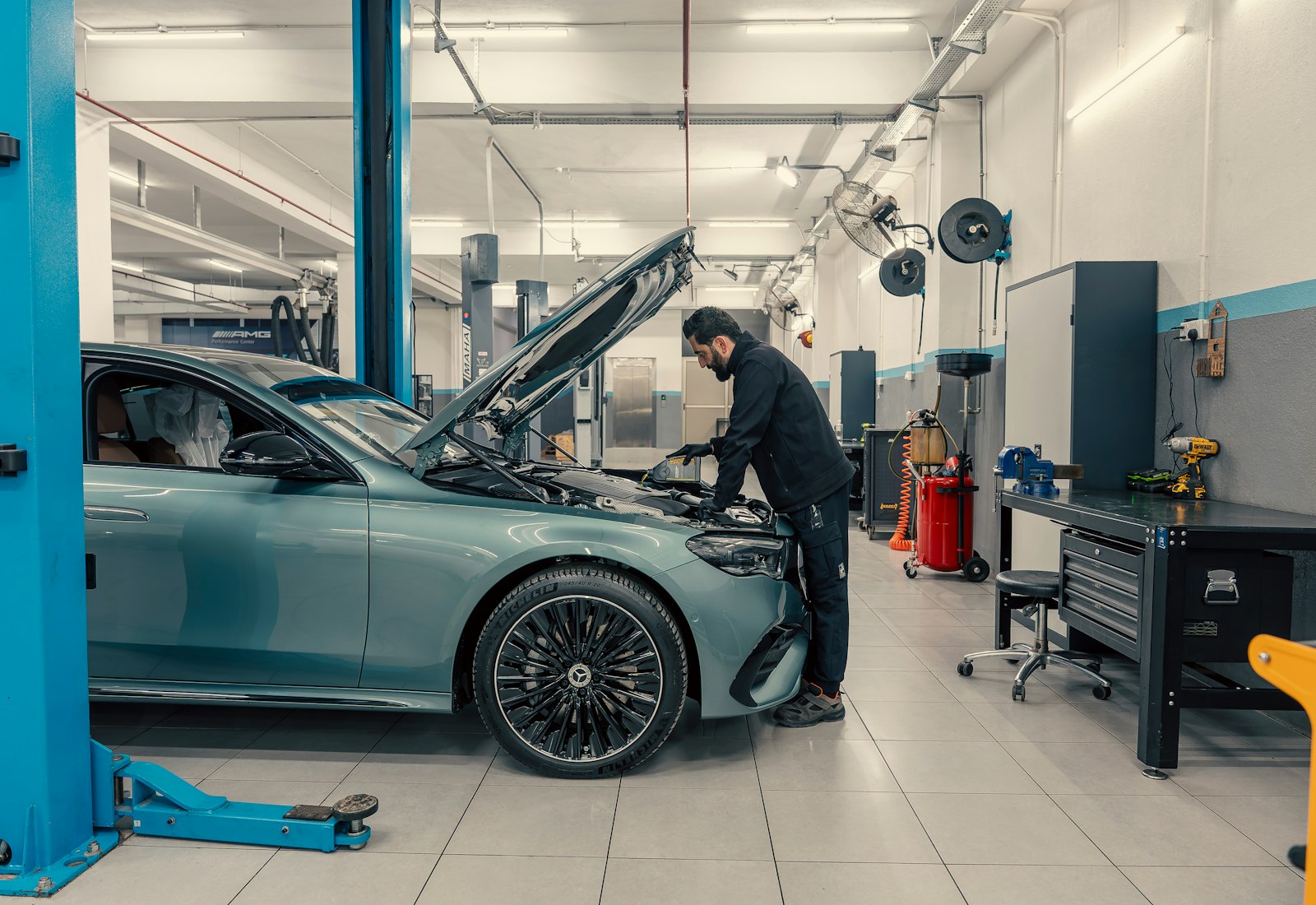 Salesforce Automotive Cloud mit Beyond Digital: Mechaniker arbeitet am geöffneten Motorraum eines Autos in einer modernen Werkstatt