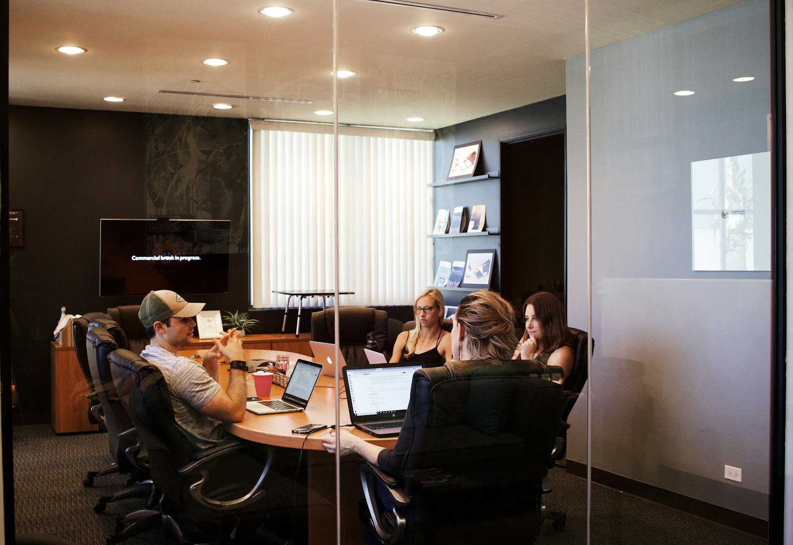 Salesforce Commerce Cloud Einführung mit Beyond Digital: Team bespricht an einem Tisch mit Laptops in einem verglasten Besprechungsraum