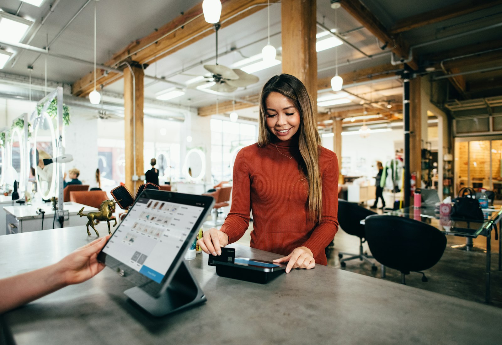 Salesforce Commerce Cloud Beratung von Beyond Digital: Kundin bezahlt an einer Ladenkasse mit Tablet-Kassensystem per Karte