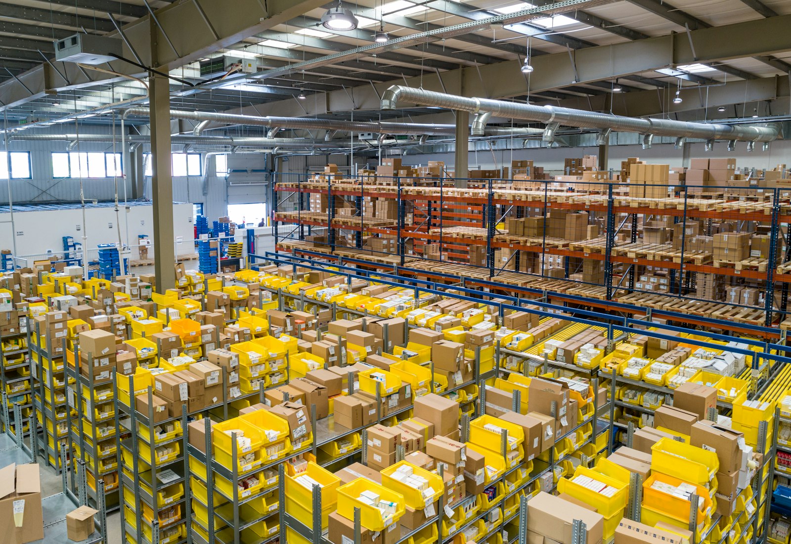 Salesforce Commerce Cloud mit Beyond Digital: Versandlager mit zahlreichen gelben Kisten und Paketen auf Regalen