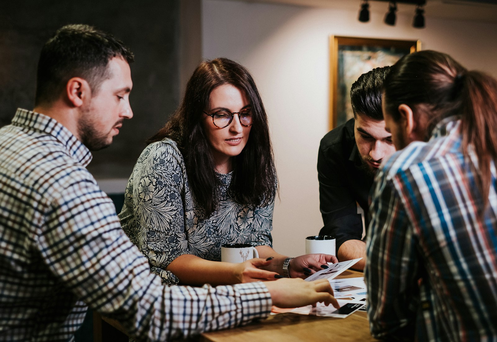 Salesforce Consumer Goods Cloud mit Beyond Digital: Vier Kollegen besprechen Unterlagen und ein Tablet an einem Holztisch