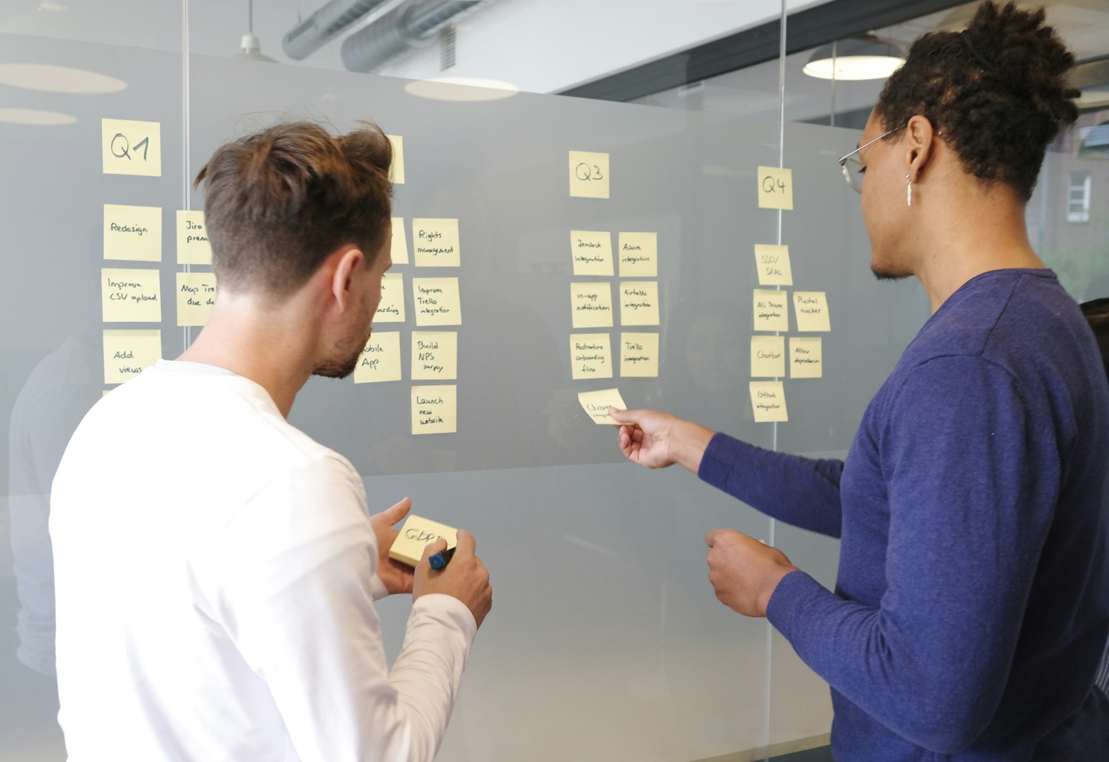 Salesforce Consumer Goods Cloud Einführung mit Beyond Digital: Zwei Personen ordnen Haftnotizen an einer Glaswand in einem Workshop