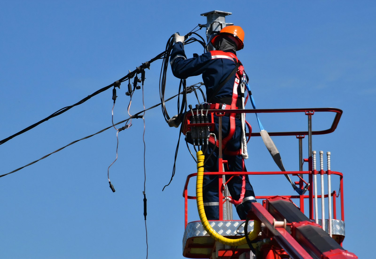 Salesforce Energy & Utilities Cloud mit Beyond Digital: Netztechniker mit Helm und Sicherungsgurt arbeitet von einer Hubarbeitsbühne an einer