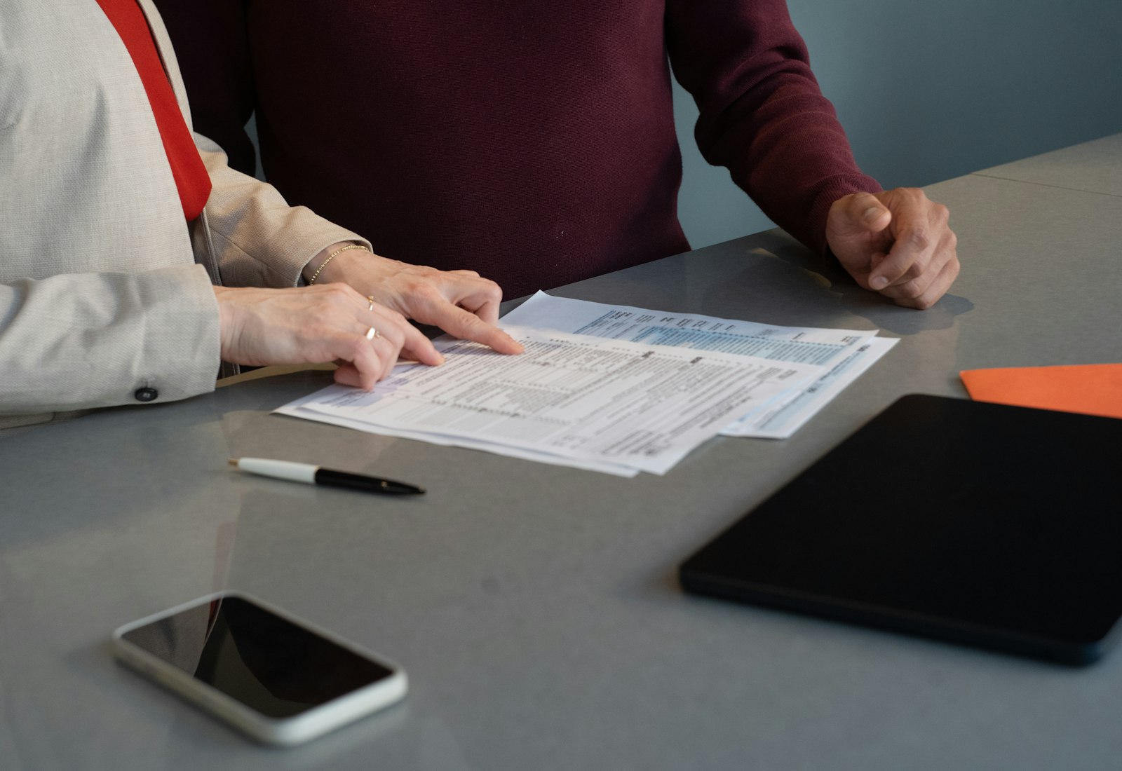 Salesforce Financial Services Cloud mit Beyond Digital: Zwei Personen prüfen Formulare auf einem Tisch, daneben Smartphone und Tablet