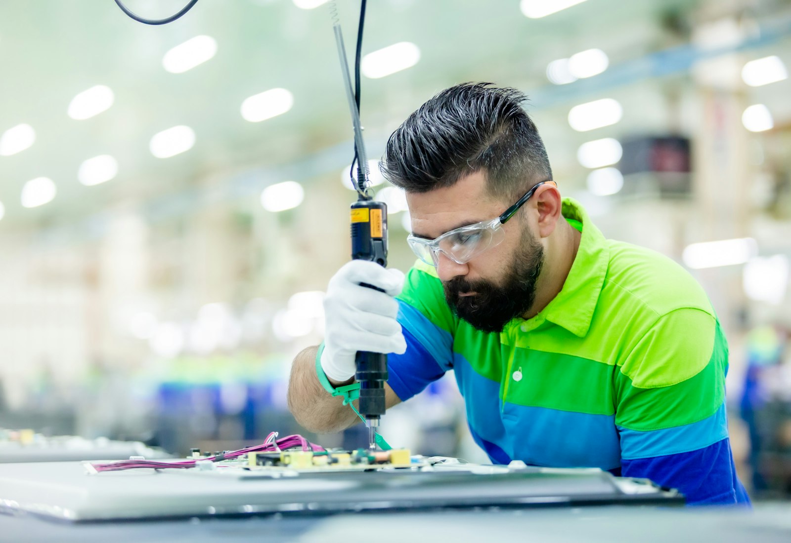 Salesforce Manufacturing Cloud Einführung mit Beyond Digital: Mitarbeiter mit Schutzbrille montiert Elektronikbauteile mit einem Akkuschrauber