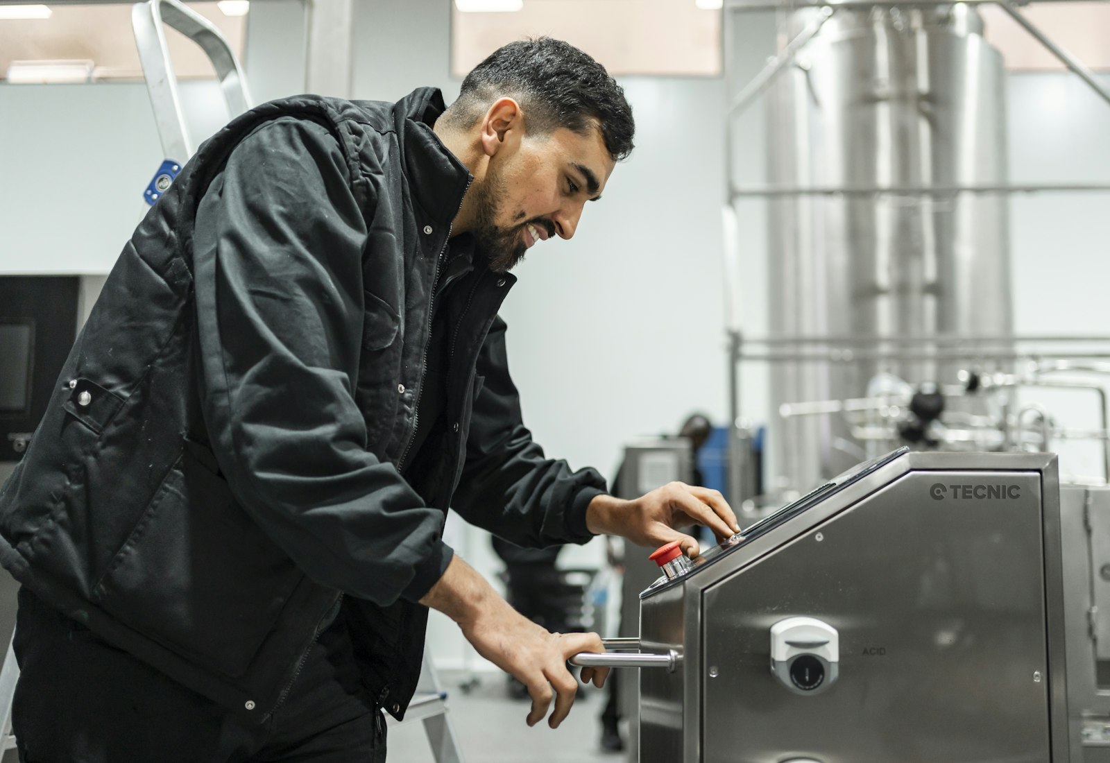 Salesforce Manufacturing Cloud mit Beyond Digital: Techniker bedient das Bedienfeld einer Edelstahlanlage in einer Produktionshalle