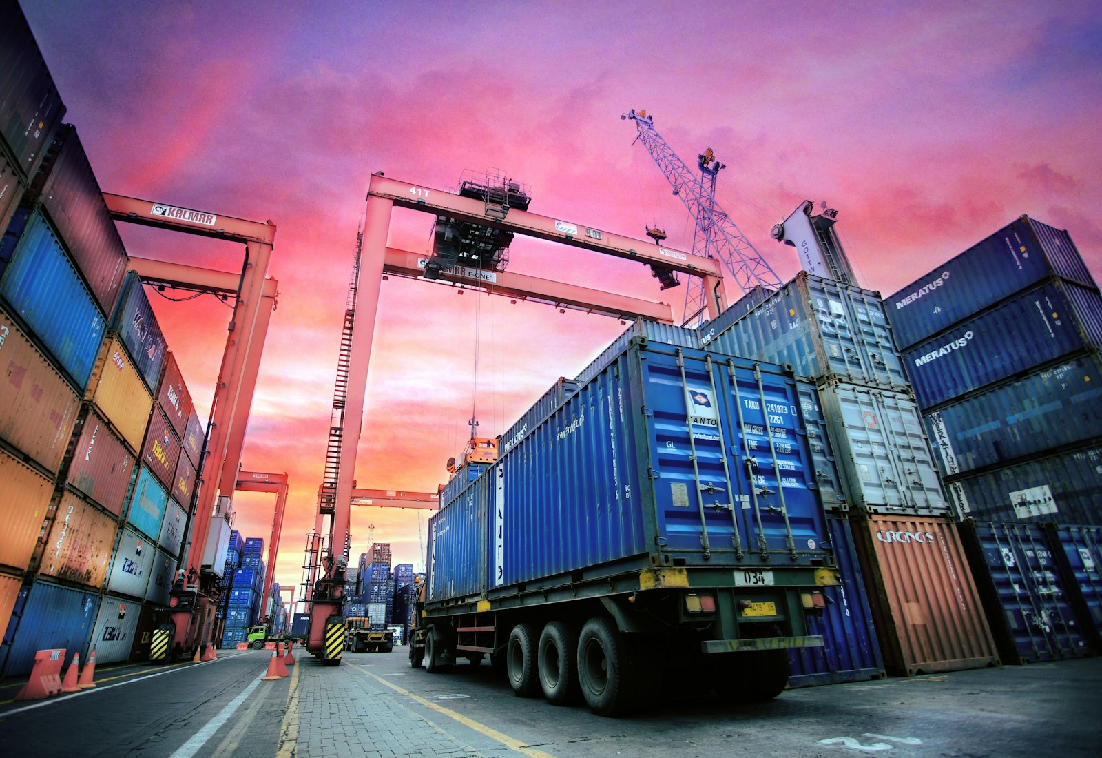 Salesforce Net Zero Cloud mit Beyond Digital: Gestapelte Schiffscontainer und ein Lkw in einem Containerhafen bei Sonnenuntergang