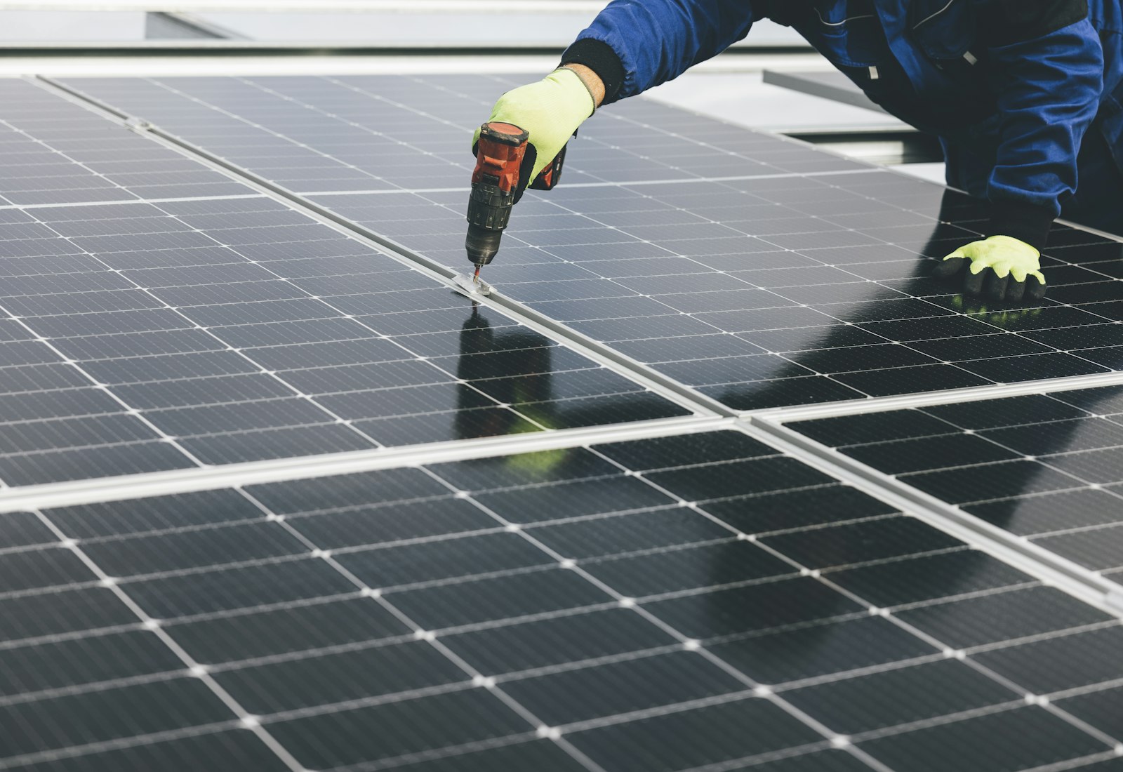 Salesforce Net Zero Cloud mit Beyond Digital: Techniker mit Arbeitshandschuhen montiert ein Solarmodul mit einem Akkuschrauber