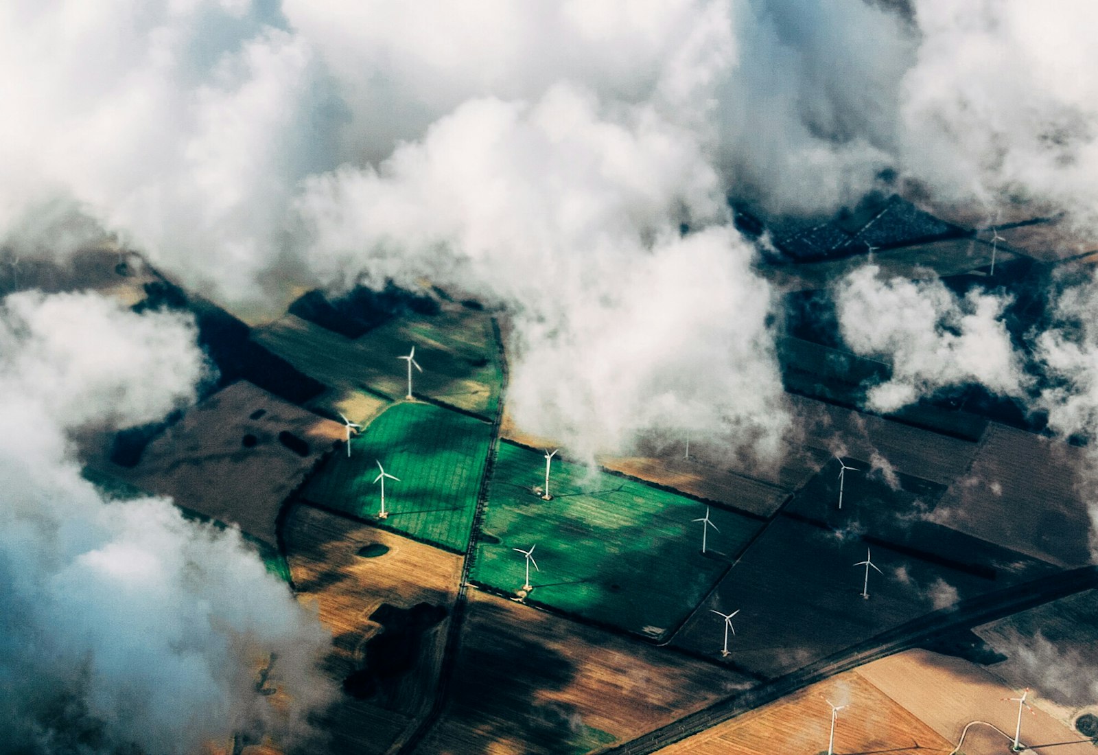 Salesforce Net Zero Cloud Beratung von Beyond Digital: Luftaufnahme von Feldern mit Windkraftanlagen unter Wolken