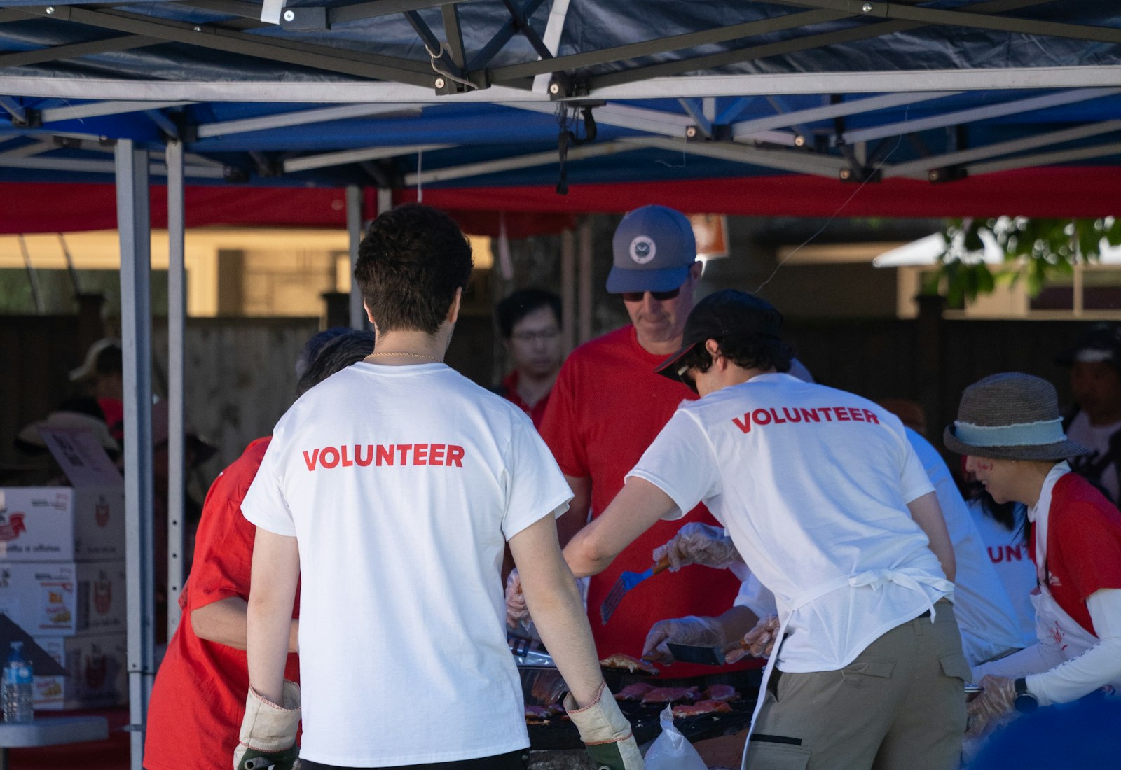 Salesforce Nonprofit Cloud mit Beyond Digital: Ehrenamtliche in Volunteer-Shirts sortieren Material unter einem blauen Zelt