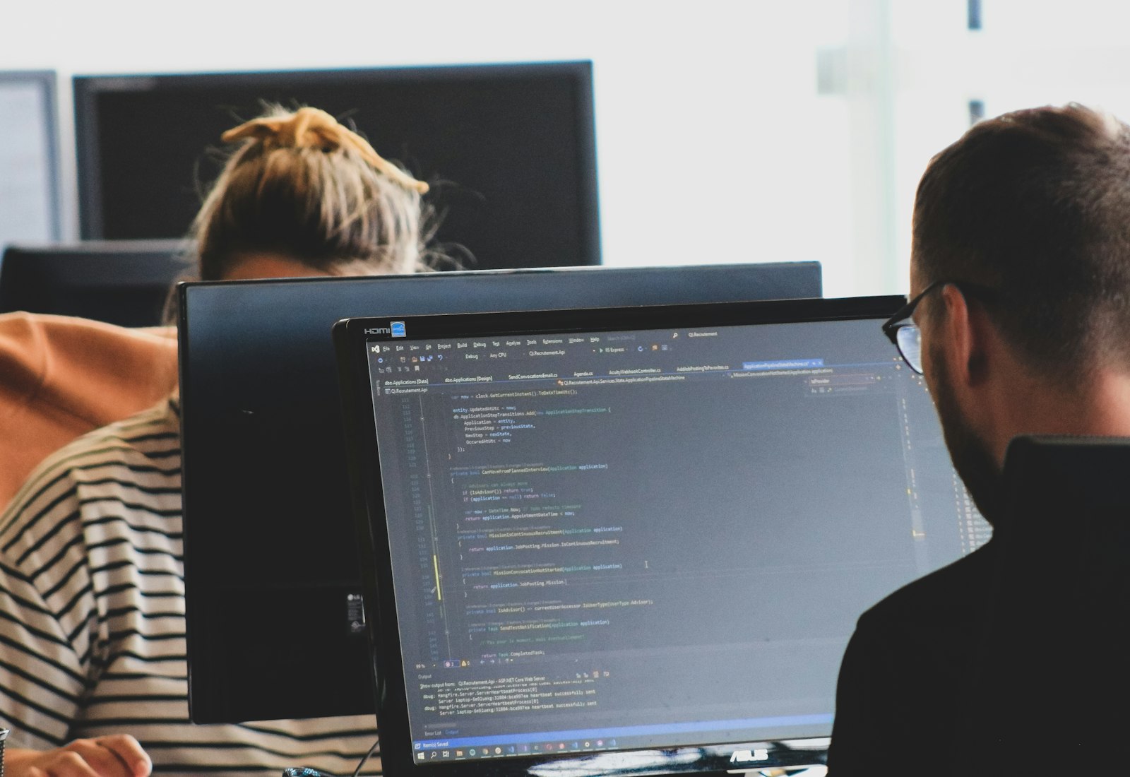 Salesforce Data Mask mit Beyond Digital: Zwei Personen arbeiten in einem hellen Büro an Monitoren mit Programmcode
