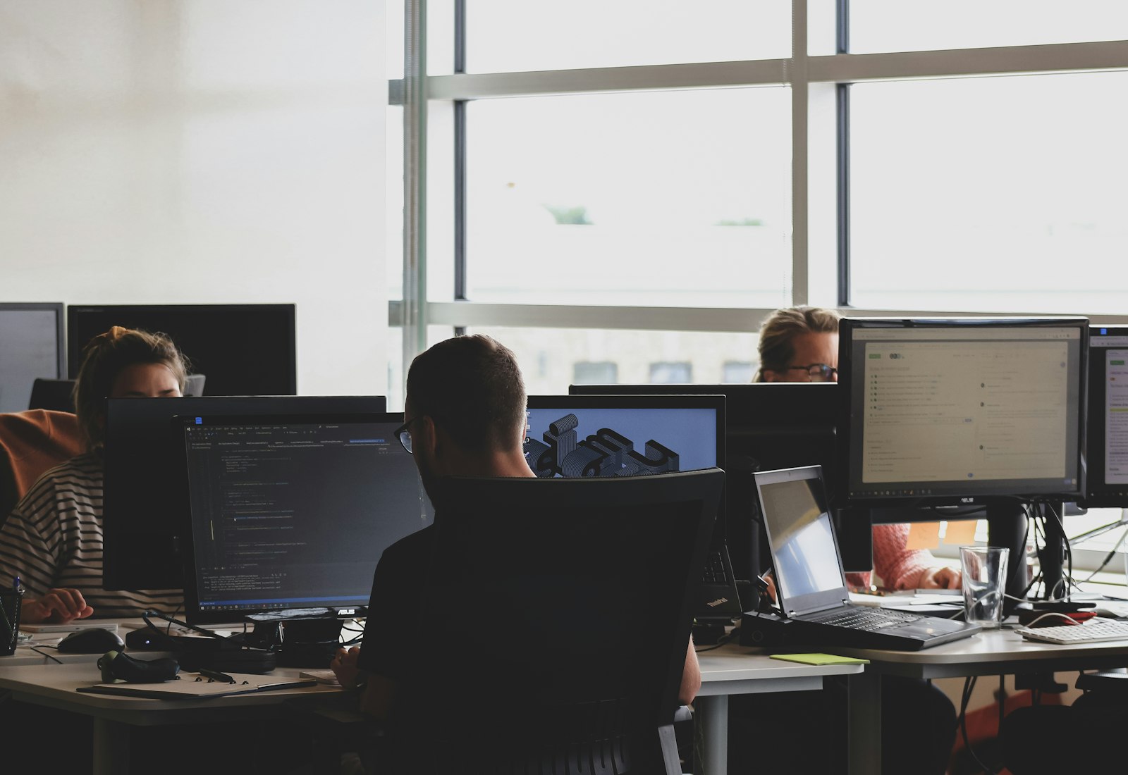Salesforce Data Mask mit Beyond Digital: Mehrere Personen arbeiten in einem Großraumbüro an Bildschirmarbeitsplätzen