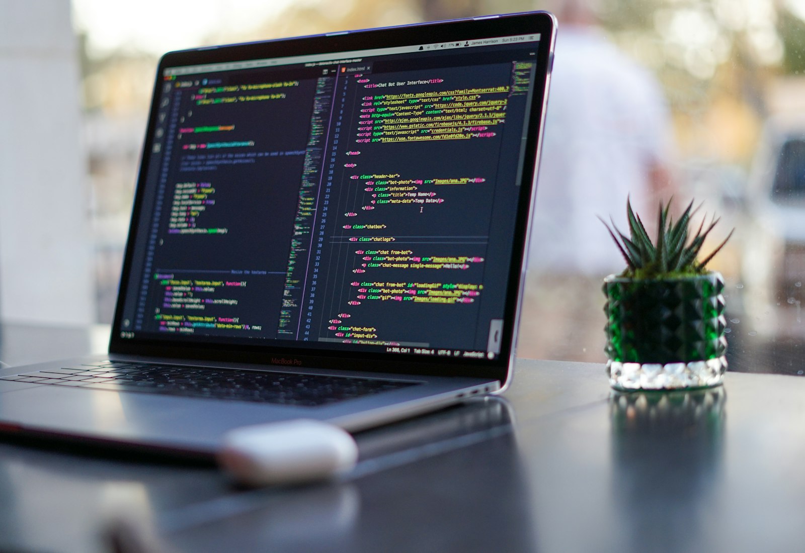 Salesforce Data Mask mit Beyond Digital: Aufgeklappter Laptop mit Programmcode auf einem Schreibtisch neben einer Pflanze