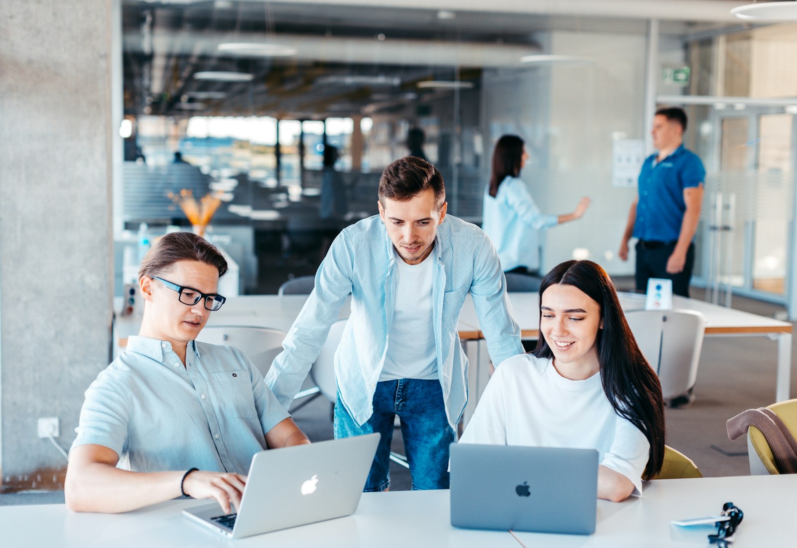 Slack Salesforce mit Beyond Digital: Drei Kolleginnen und Kollegen arbeiten gemeinsam an Laptops in einem hellen Großraumbüro