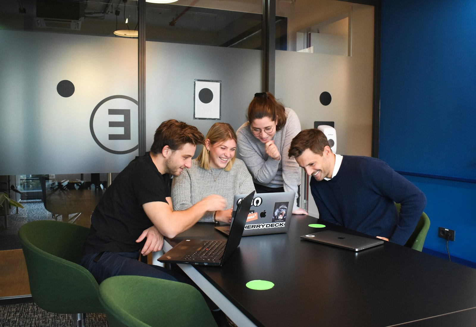 Slack Salesforce Einführung mit Beyond Digital: Vier Personen beugen sich in einem Besprechungsraum gemeinsam über einen Laptop