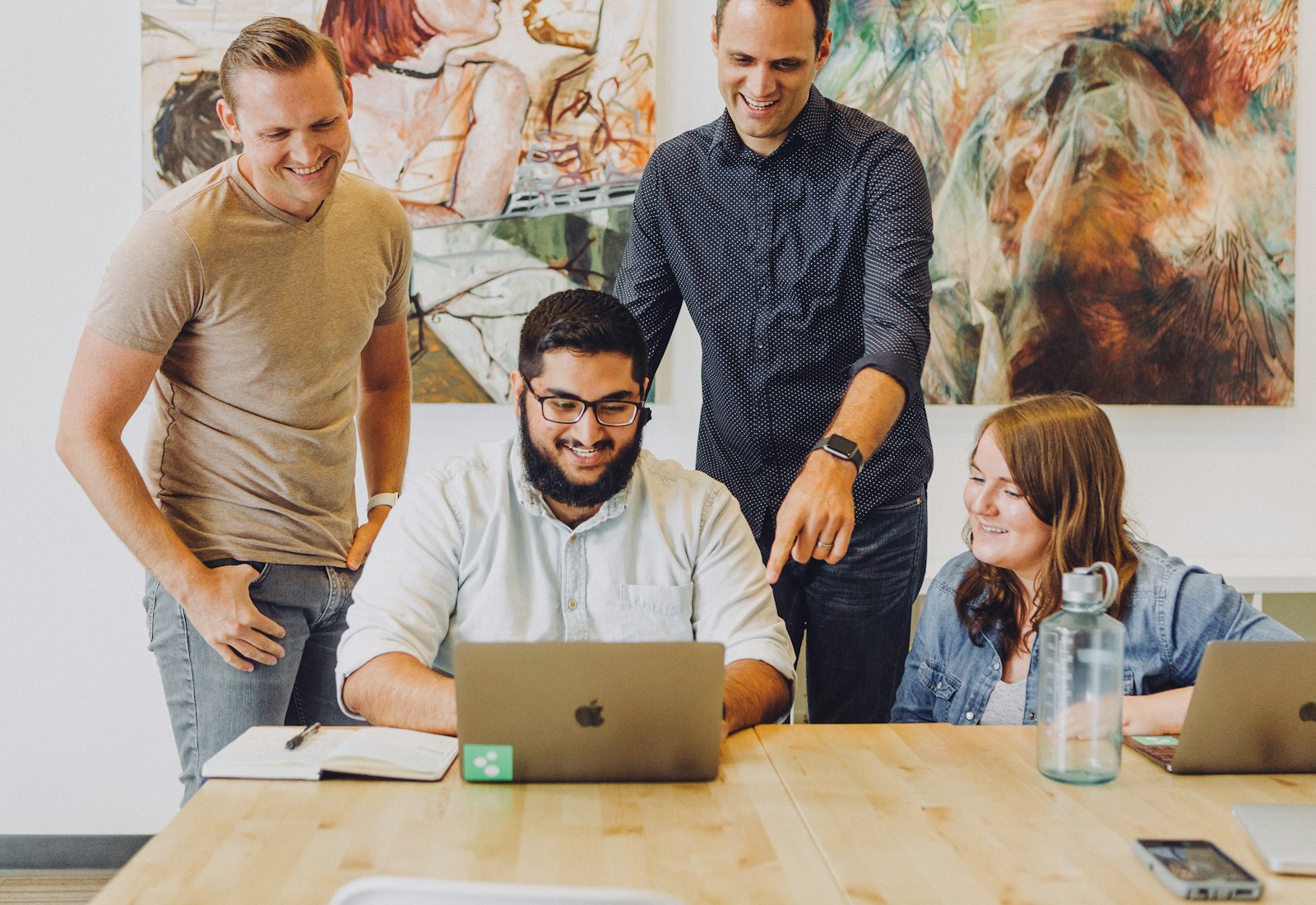 Slack Salesforce mit Beyond Digital: Vier Kolleginnen und Kollegen schauen gemeinsam auf einen Laptop und besprechen die nächsten