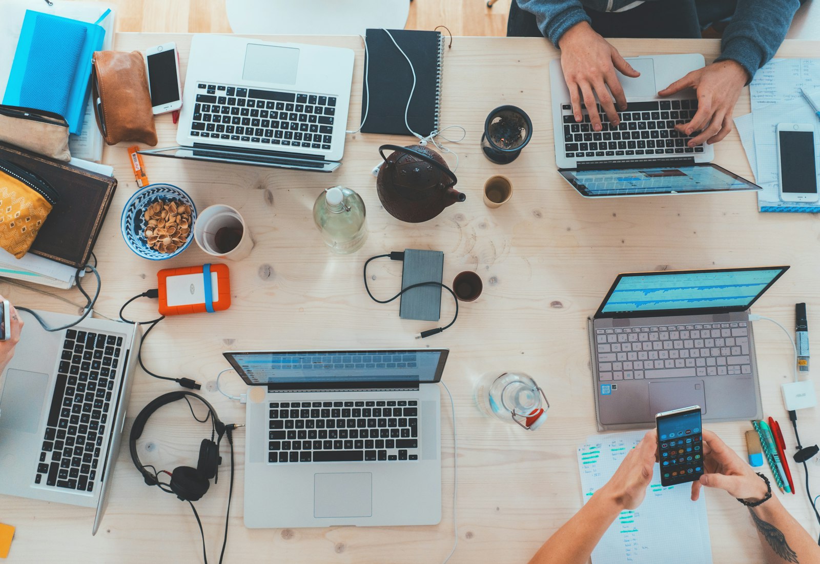 Slack Salesforce mit Beyond Digital: Draufsicht auf einen Holztisch, an dem mehrere Personen mit Laptops, Smartphone und Notizen