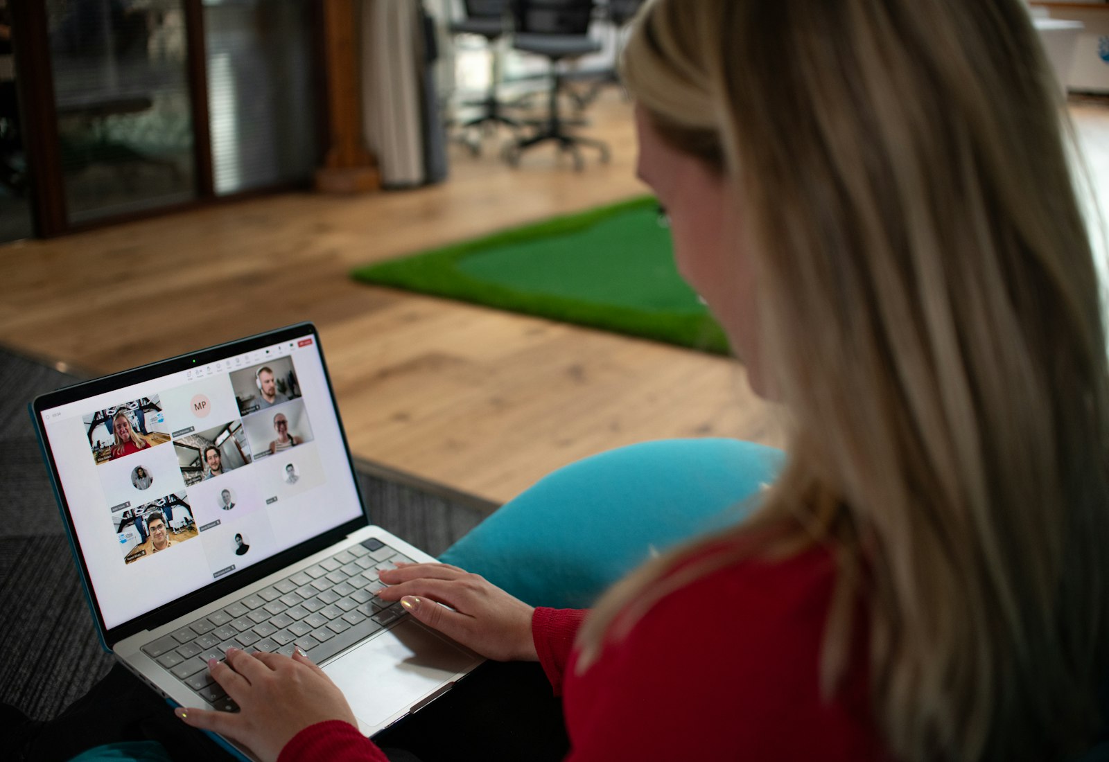 Slack Salesforce mit Beyond Digital: Frau arbeitet im Büro an einem Laptop, auf dem eine Videokonferenz mit mehreren Teilnehmenden