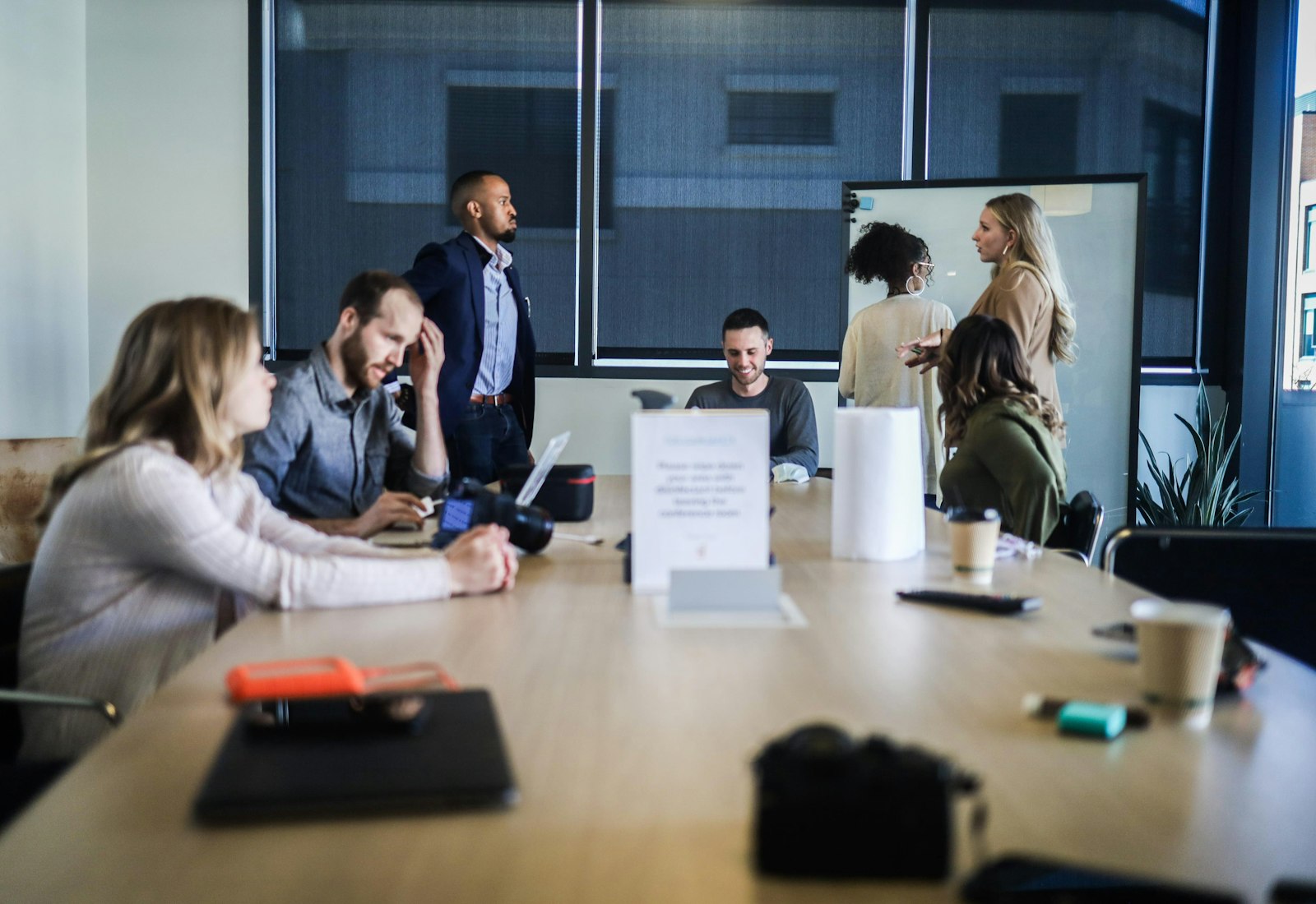 Tableau Salesforce Beratung von Beyond Digital: Mehrere Personen sitzen in einem hellen Besprechungsraum um einen Tisch, eine Person steht und