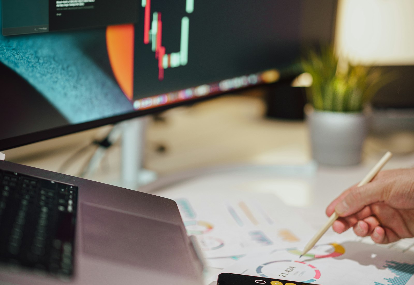 Tableau Salesforce mit Beyond Digital: Person notiert Ergebnisse auf Papier, im Hintergrund ein Monitor mit Börsenchart und ein