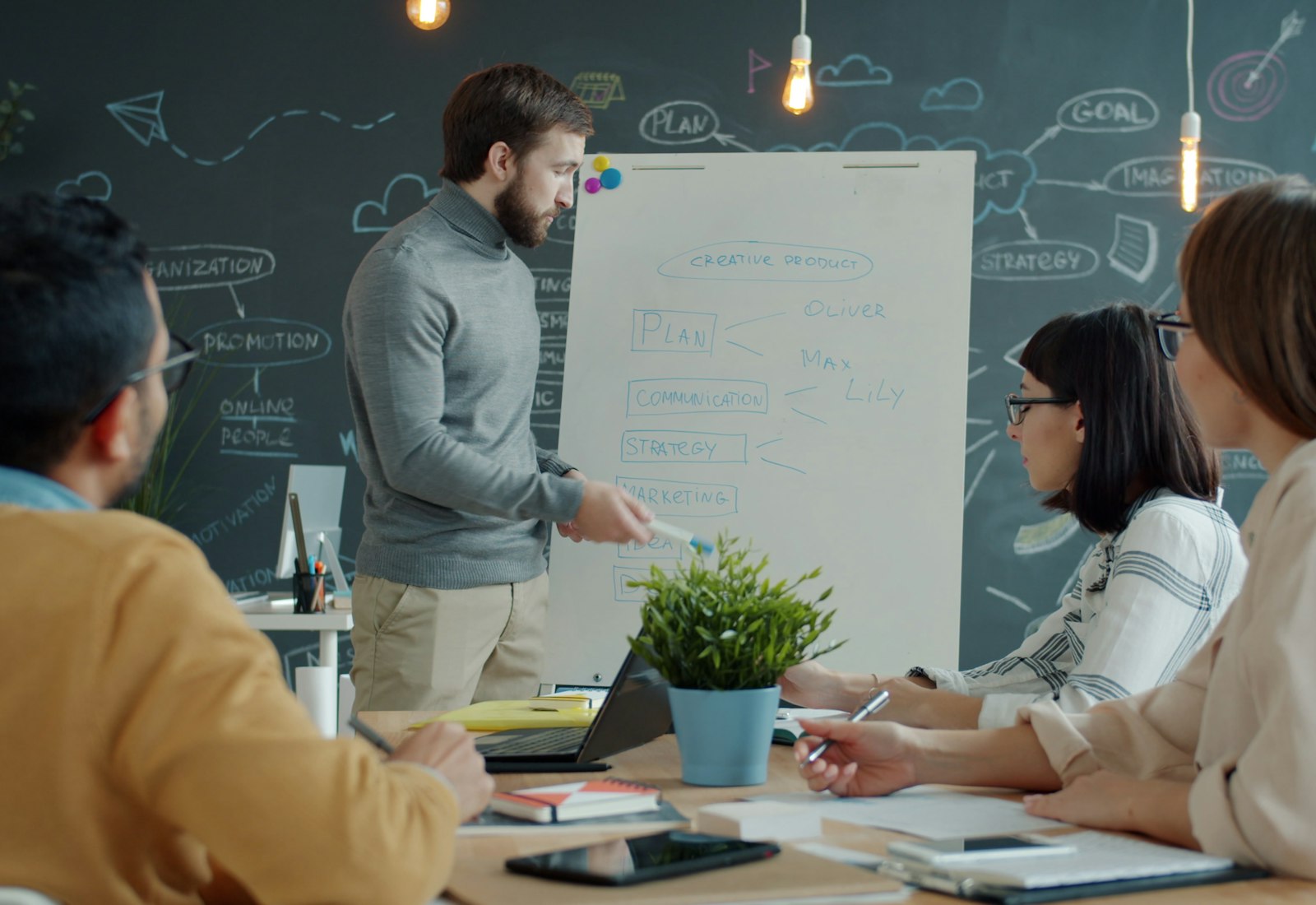 Tableau Salesforce Einführung mit Beyond Digital: Ein Berater erklärt am Flipchart vor einer Tafel mit Skizzen, drei Kolleginnen und Kollegen